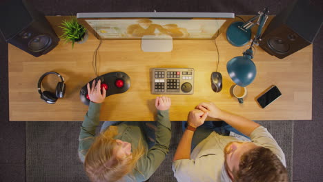 Overhead-View-Of-Male-And-Female-Video-Editor-Working-At-Computer-In-Creative-Office-At-Night