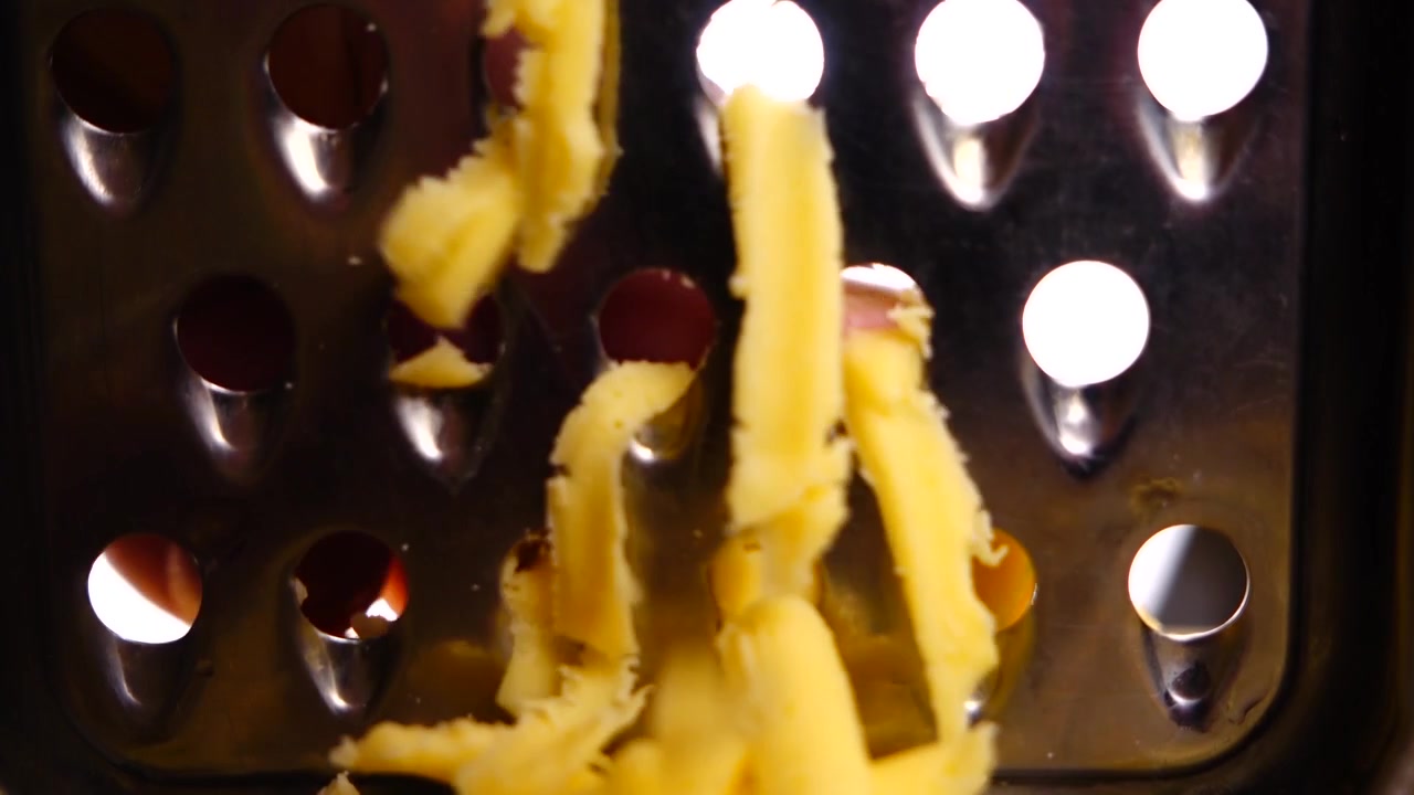 The cheese is rubbed on a grater. Shooting macro.