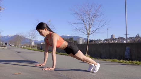 mujer joven haciendo ejercicio al aire libre flexiones elevadas plano general