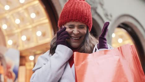 Mujer-Emocionada-Con-Bolsas-De-Compras-Hablando-Por-Teléfono-Móvil