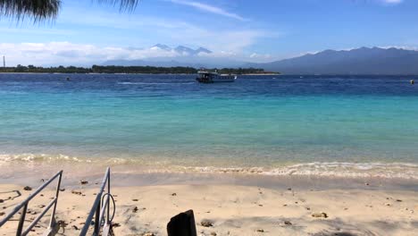 boat sailing away to lombok with blue water and mountain view in gili trawangan, bali, indonesia