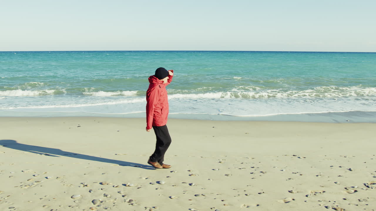 Man Collects Stones During a Winter Walk by the Sea