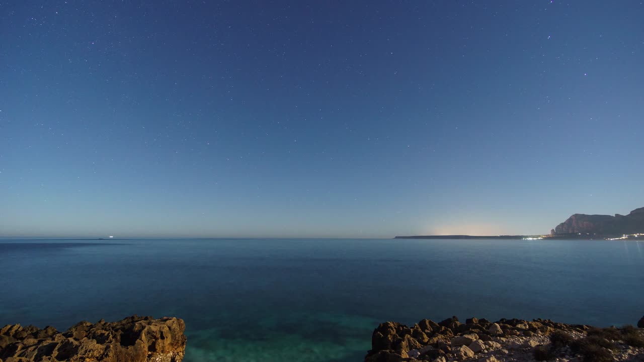 시칠리아의 몬테 코파노 (monte cofano) 자연보호구역의 은 은 물과 함께 지중해의 바위 해안선 위에 밤에 별이 있습니다.