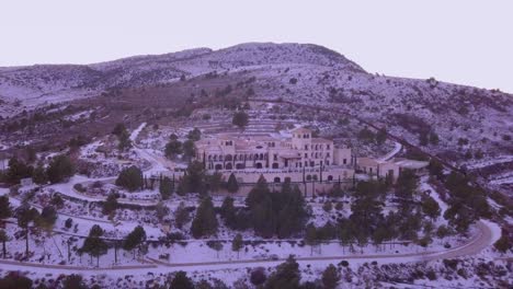 Dron-Panorámico-En-Un-Hotel-Durante-La-Puesta-De-Sol-En-Las-Montañas-De-España-Con-Nieve