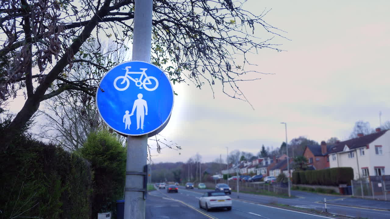 파란색 자전거 타는 사람과 보행자는 영국 포장 도로의 길가에 서명합니다.