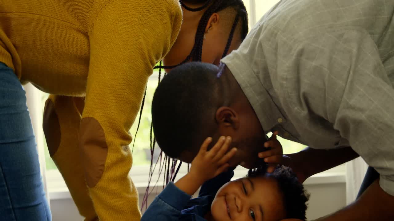 vista lateral de jóvenes padres negros jugando con su hijo en una casa cómoda 4k