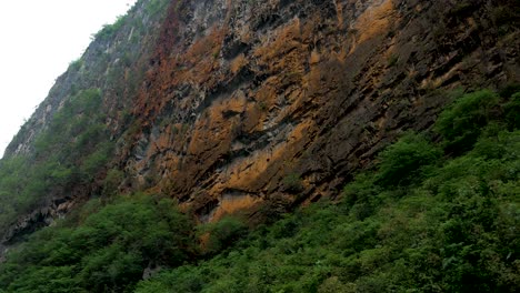 Zerklüfteter-Und-Verfallener-Kalksteinfelsen-Am-Hang-Eines-Berges-Mit-Vegetation-Darunter