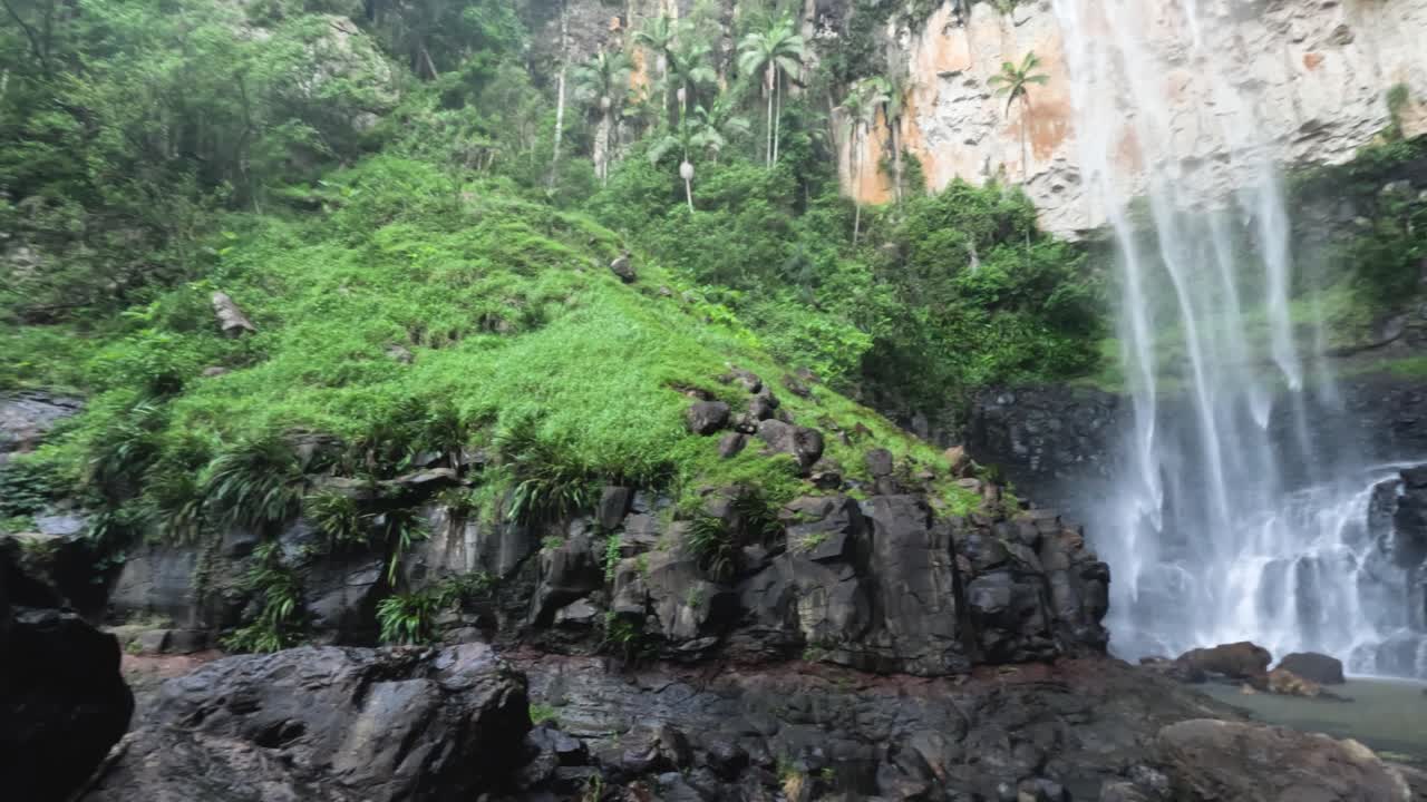 persona disfrutando de una cascada en la vegetación exuberante