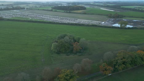 Strafing-from-the-left-towards-the-right-aerial-drone-shot-of-an-agricultural-land-and-a-piggery-farm-in-background,-located-in-the-outskirts-of-Thetford,-east-of-London-in-United-Kingdom