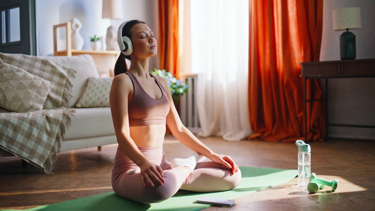 Garota asiática esportiva navegando no telefone antes da meditação de yoga. Posição de lótus no tapete de casa