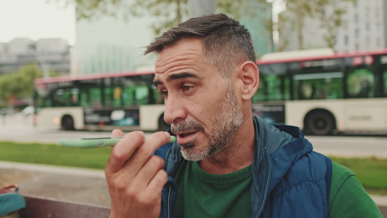 Mann som bruker telefon i byen med buss i bakgrunnen