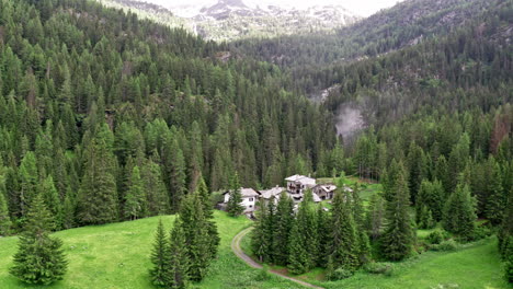 Cascate-del-rutor's-lush-green-forest-and-a-winding-path-leading-to-a-secluded-house,-aerial-view