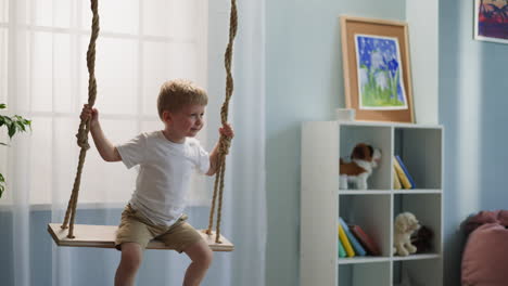 Toddler-boy-exclaims-and-laughs-contentedly-on-swing-at-home