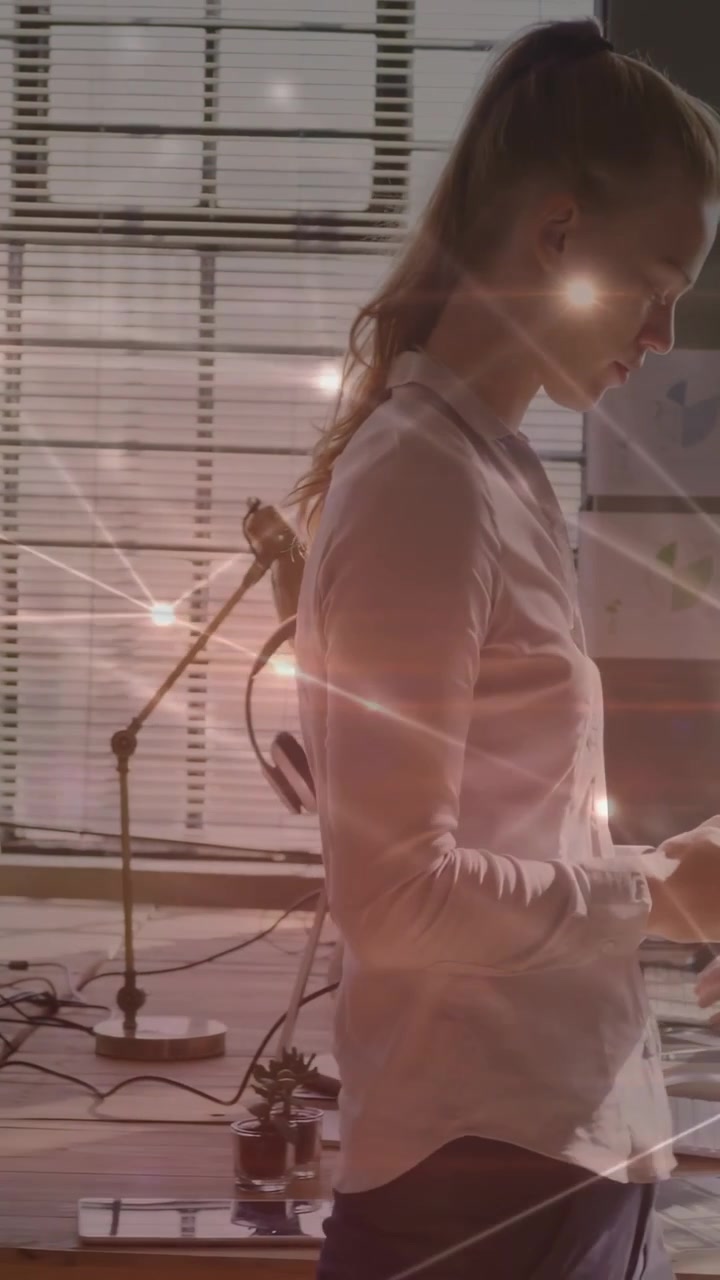 Vertical video: Woman reading phone moving to office keys to work causing sparkle while man typing
