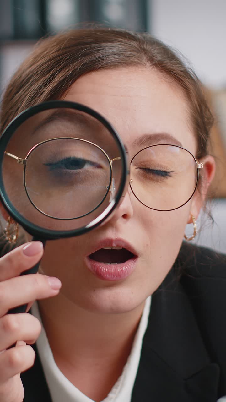 Business woman holding magnifying glass near face looking with big zoomed eye searching analysing