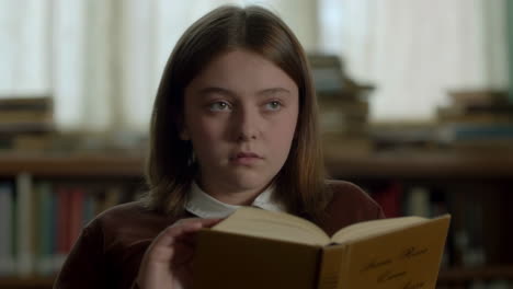 una chica leyendo un libro en una biblioteca.