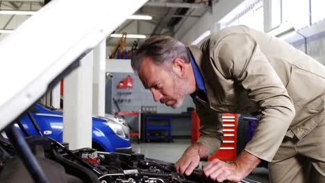 mecánico usando una tableta digital mientras hace servicio a un motor de automóvil