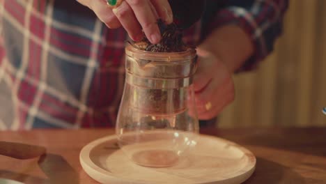 hand selecting dried tea leaves for brewing with glass tea press
