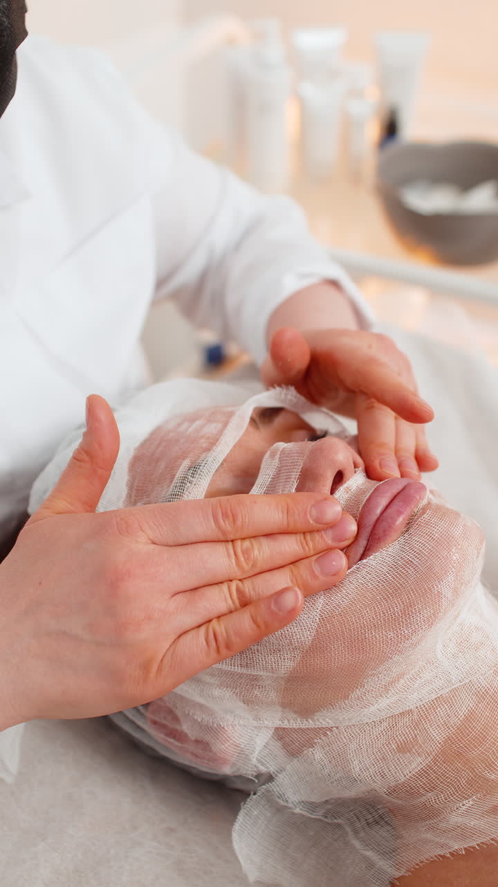 Donna che completa la procedura della maschera di avvolgimento facciale nella clinica di cosmetologia estetista applica garza per la cura della pelle