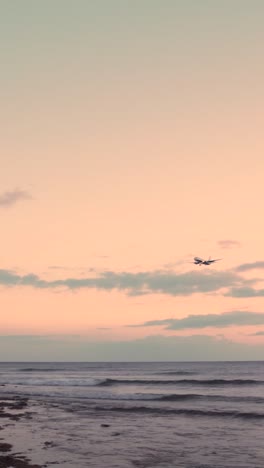 airplane landing over the ocean at sunset