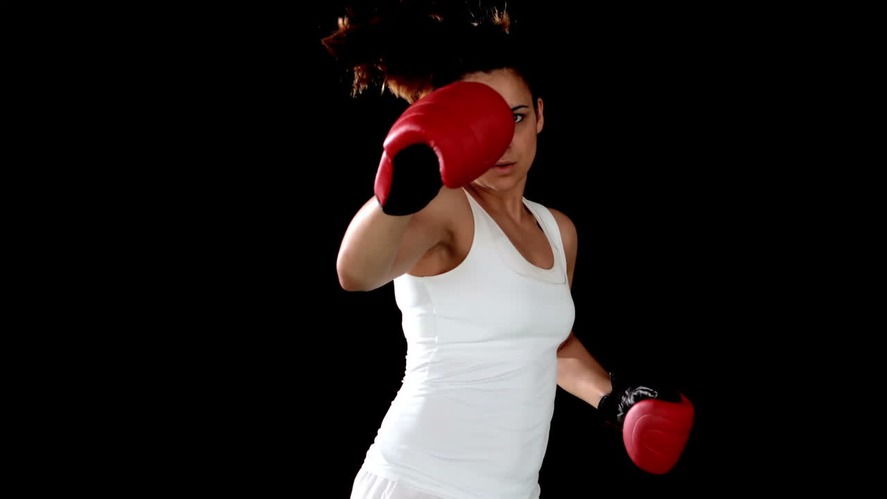 una morena golpeando con guantes de boxeo.