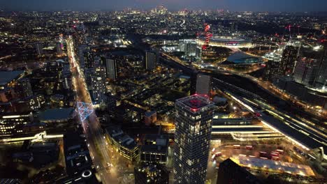 Rascacielos-Futuristas-Del-Centro-De-Lujo-De-Stratford-Caminos-Brillantes-En-La-Noche-Vista-Aérea-Vuelo-Lento-Hacia-Adelante