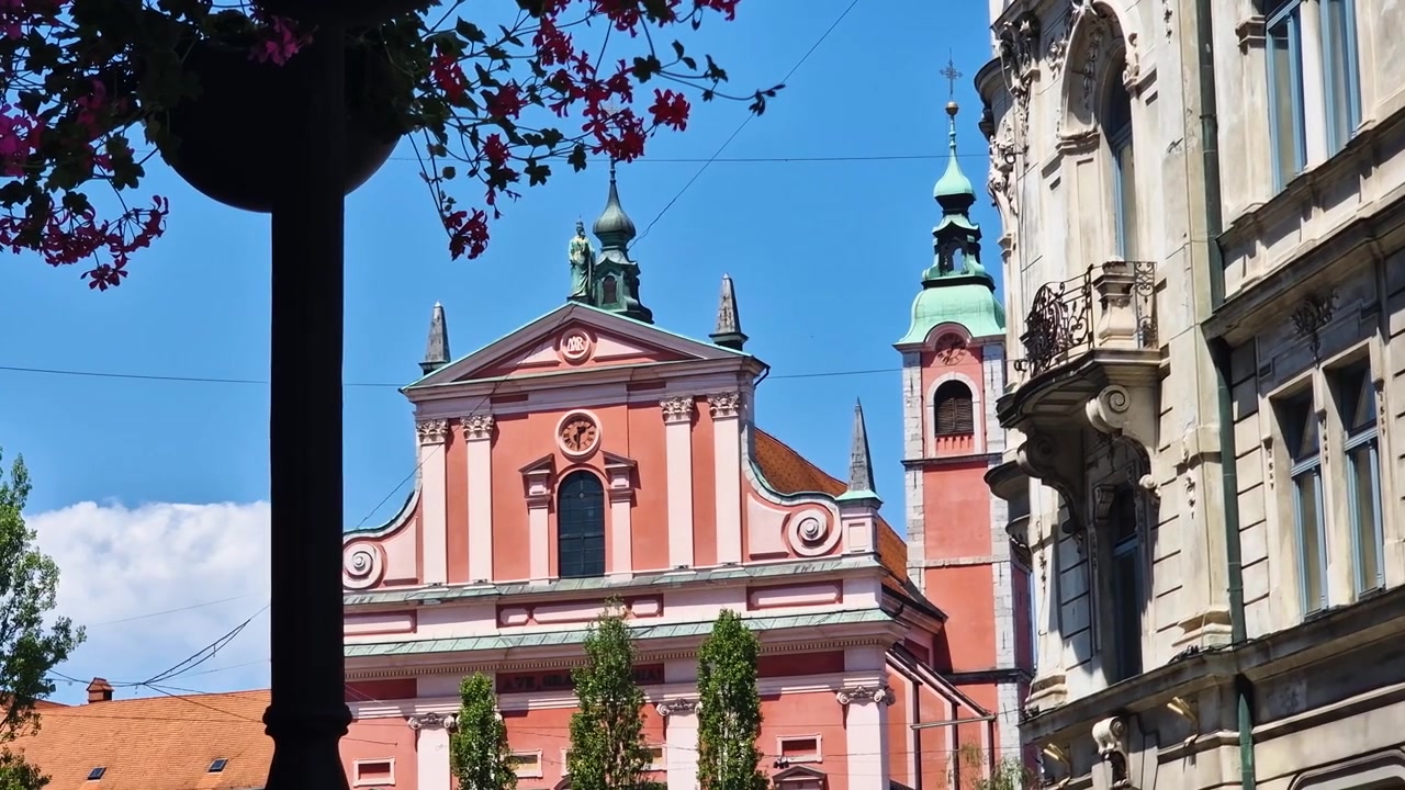Lubiana, Slovenia, Chiesa Francescana con facciata rosa, punto di riferimento della città in una soleggiata giornata estiva.