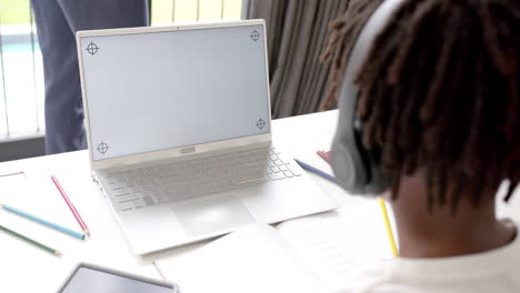 african american boy using laptop with copy space on screen for online lesson at home, slow motion