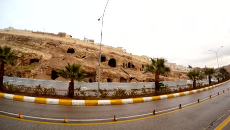 empty very old cave city in centre of shanlyurfa cars drive in front of camera