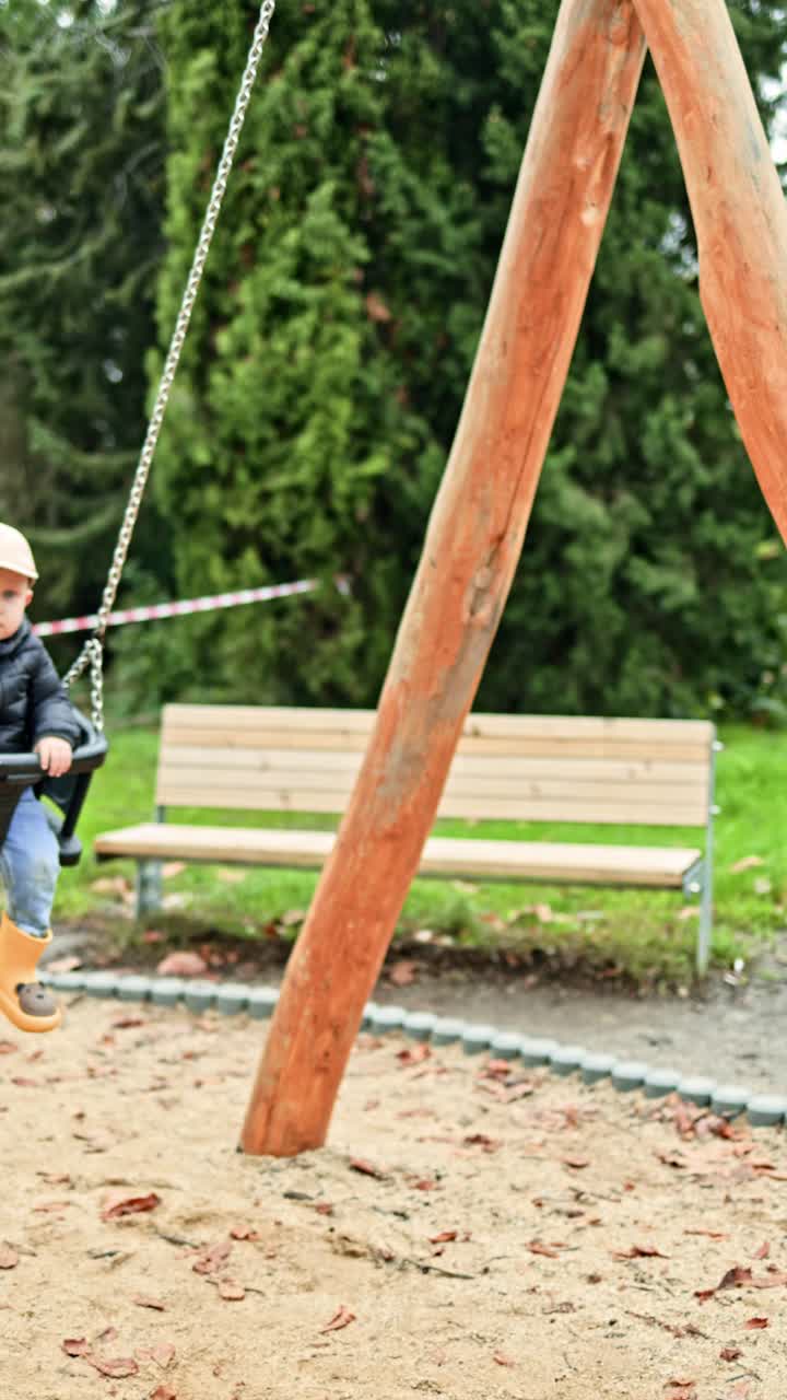 Bambino piccolo che si dondola su un'altalena in un parco giochi. Un bimbo che si dondola su un'altalena in un parco cittadino. Bambino che gioca all'aperto nella natura.