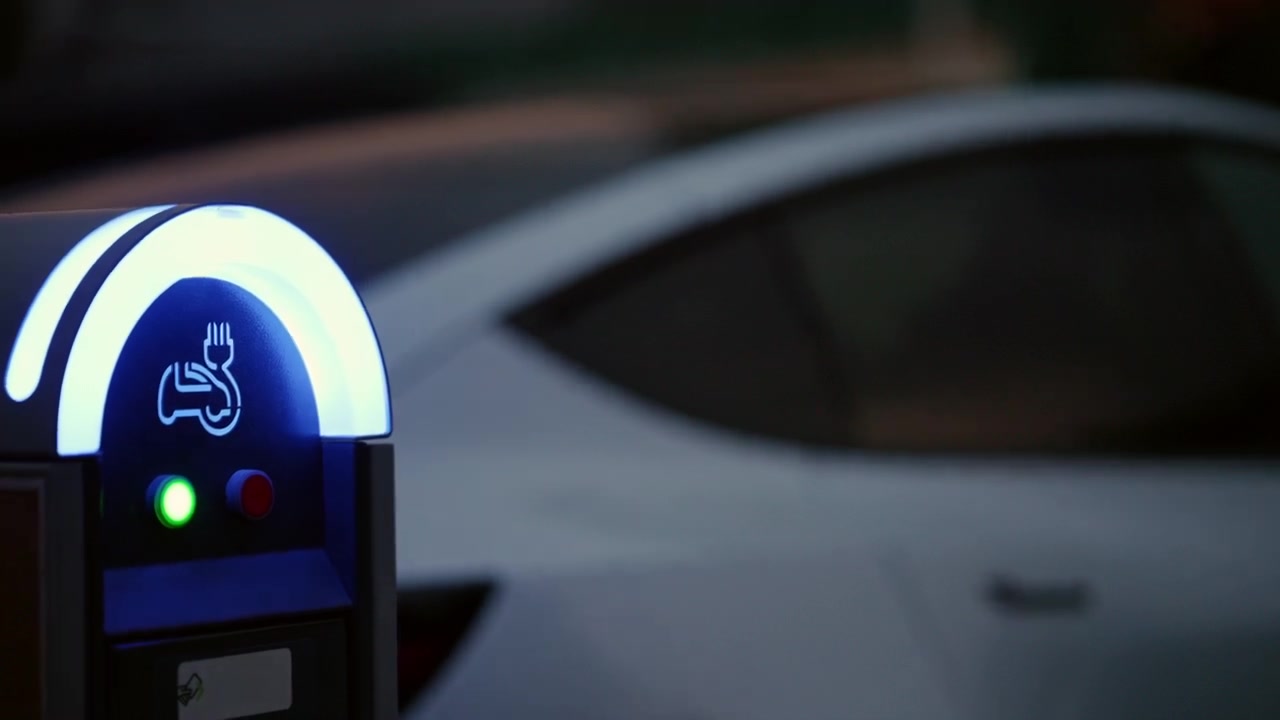 Arka planda bir elektrikli araç için uygun bir port olduğunu gösteren, mavi ışık yayan elektrikli araç şarj istasyonu.
