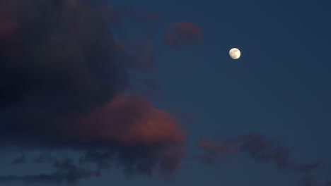 view of the moon in the pre-twilight sky in a winter time-lapse