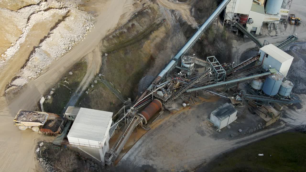 At a German limestone quarry and lime processing plant, a rock truck dumbs into the feeder of a conveyor system
