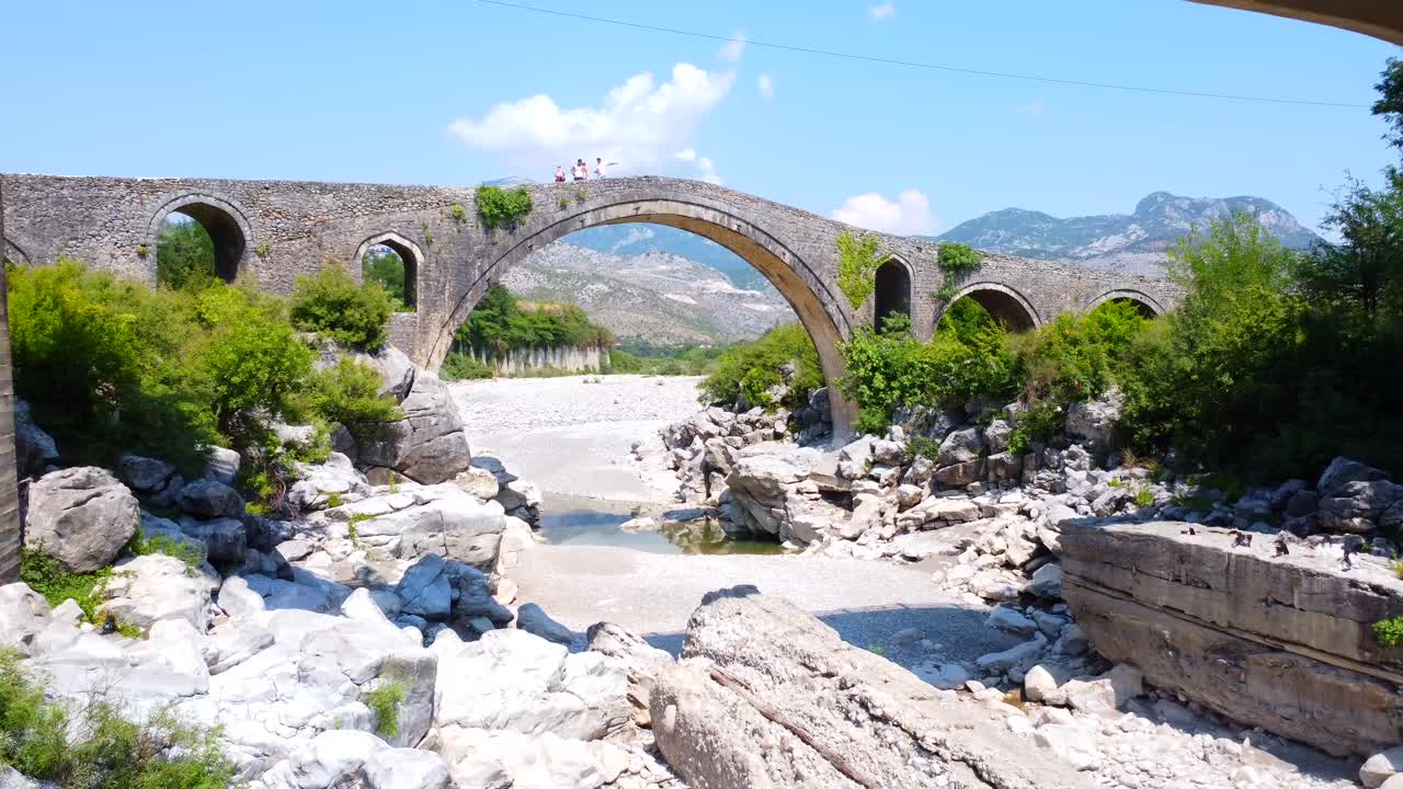 Pittoresco ponte in pietra sul fiume con montagne sullo sfondo
