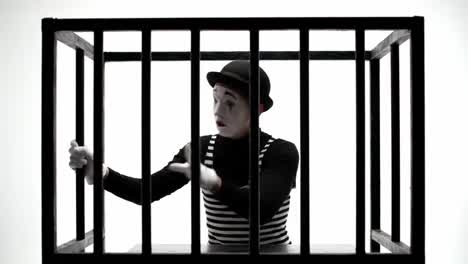 a dramatic performance of a mime artist captured in a cage, expressing emotions and themes of confinement and freedom through gesture and expression