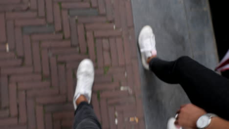 a couple with white shoes walk through the streets