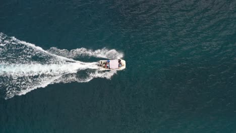 Pequeño-Barco-Blanco-Acelerando-A-Través-Del-Océano-Vista-Aérea-Hacia-Abajo