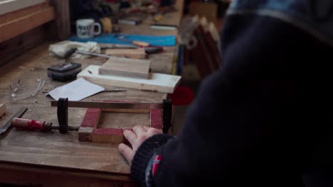 man screwing corners of wooden box secure with a clamp