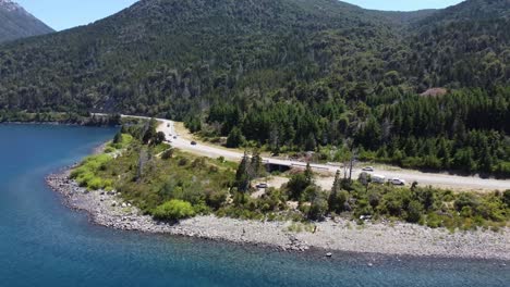 cars traveling on the road through lake and mountain in villa la angostura patagonia argentina
