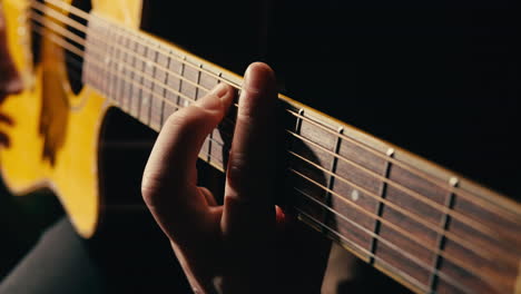 young musican man checking strings of acoustic guitar close-up. male guitarist tuning sound of musical instrument.