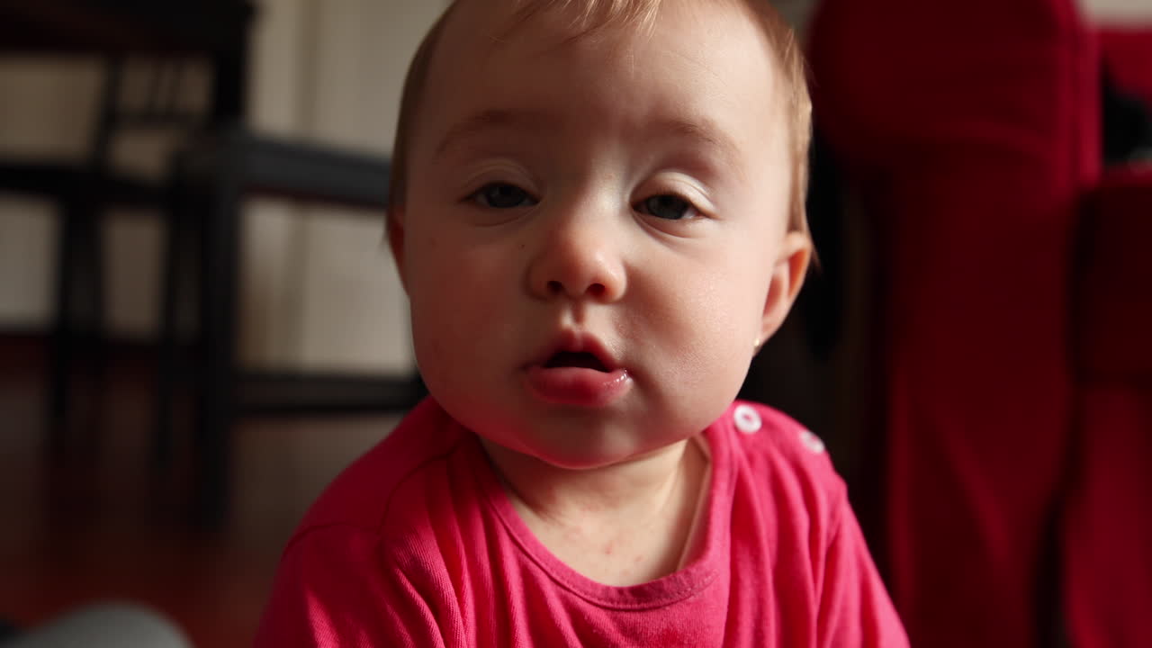 귀여운 작은 아기가 미소를 짓고 카메라를 쳐다보며 슬로우 모션으로 촬영합니다.