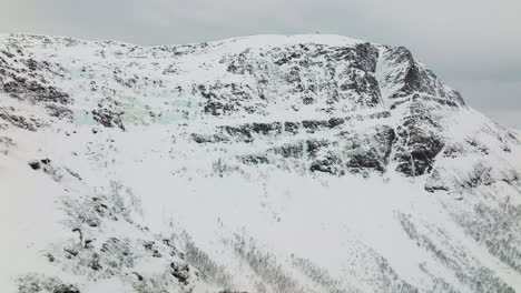 Snowy-Rocky-Mountain-Summit-In-Winter-Landscape-In-Norway,-Aerial