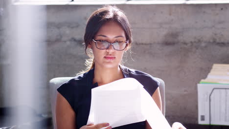 joven mujer de negocios comprobando papeles en su oficina