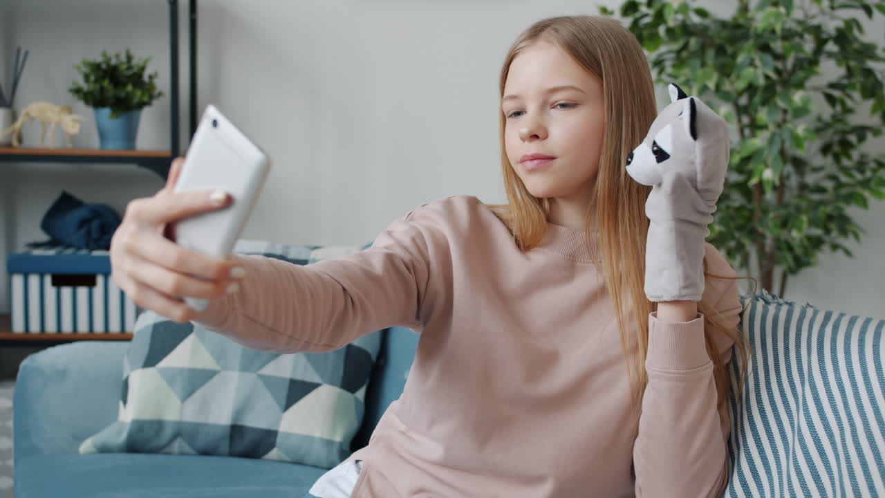 Teenage girl taking a selfie with a raccoon hand puppet