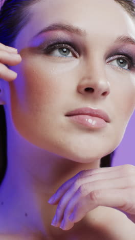 vertical video of caucasian woman with brown hair and make up touching face, copy space, slow motion