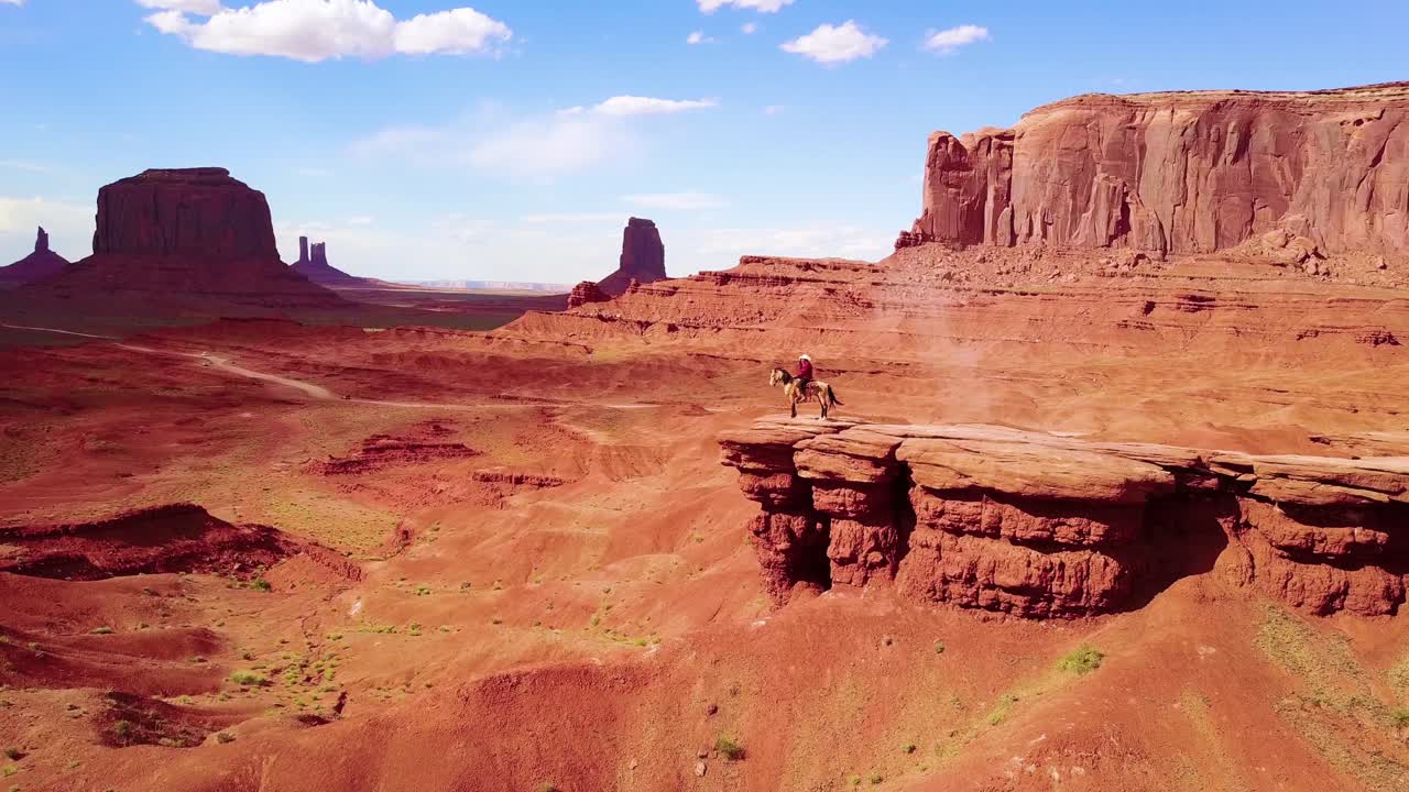 excelente antena sobre un vaquero a caballo con vistas a monument valley, utah