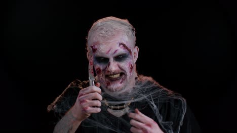 zombie sinister dead halloween man holding bloody knife trying to scare and kill in dark studio room