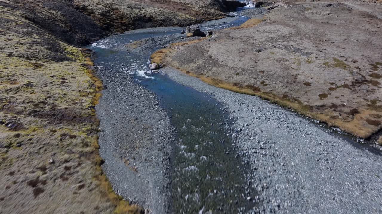 un dron volando con gracia sobre el terreno accidentado y el río que fluye, capturando la pintoresca cascada skutafoss en todo su esplendor