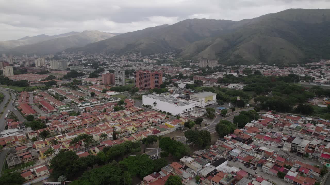 Una ripresa mozzafiato realizzata con un drone si avvicina lentamente per immortalare la pacifica coesistenza tra una città vivace e la maestosa catena montuosa verde che la circonda