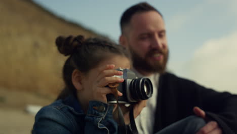 small kid holding camera making pictures of sea beach landscape family trip.